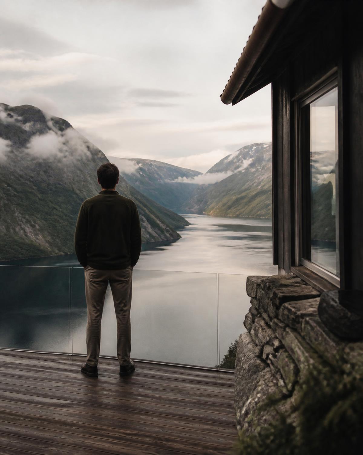 A man overlooking a quiet mountain fjord from a secluded terrace